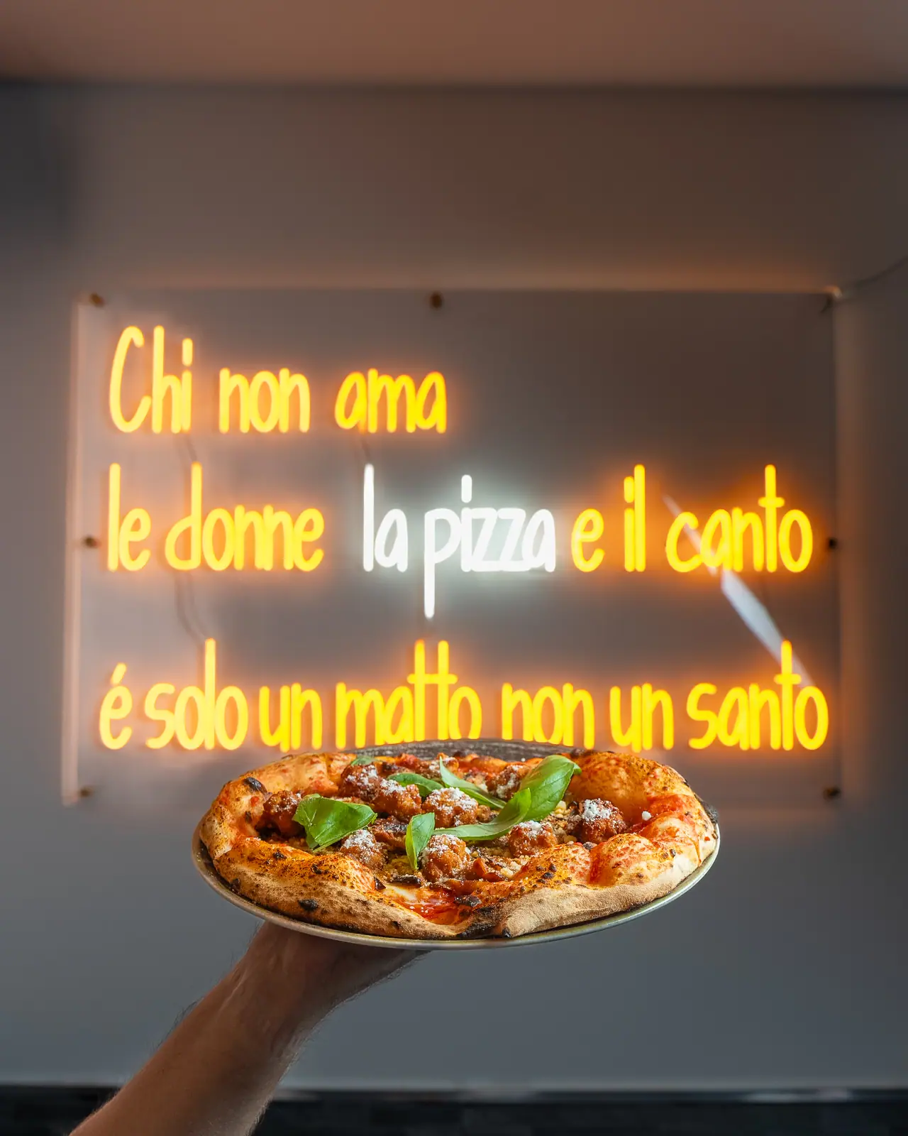 Una pizza sotto l’insegna al neon del locale