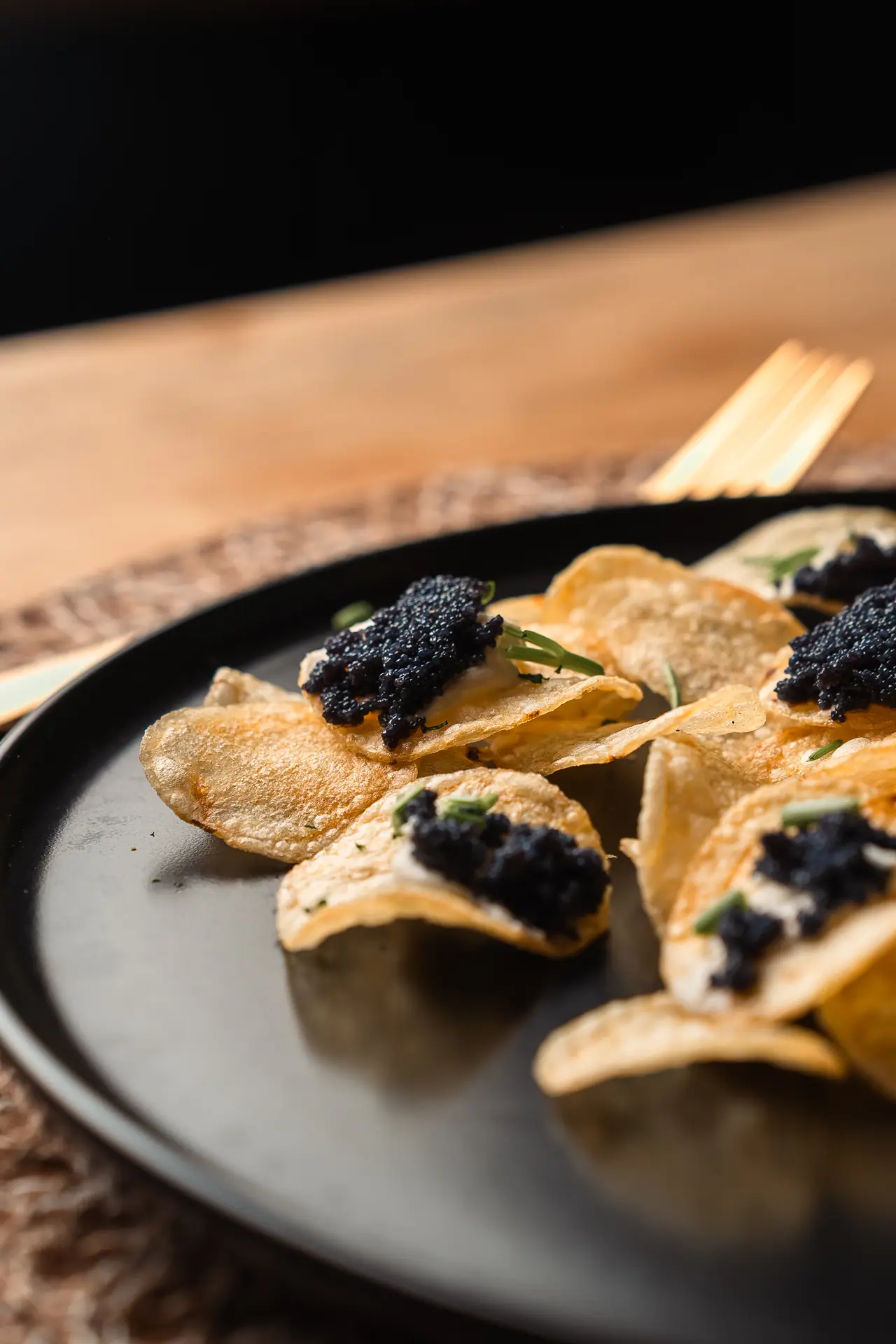 Chips con caviale su piatto scuro