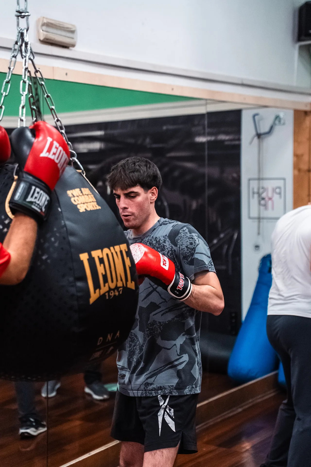 Un ragazzo colpisce il sacco da boxe in palestra