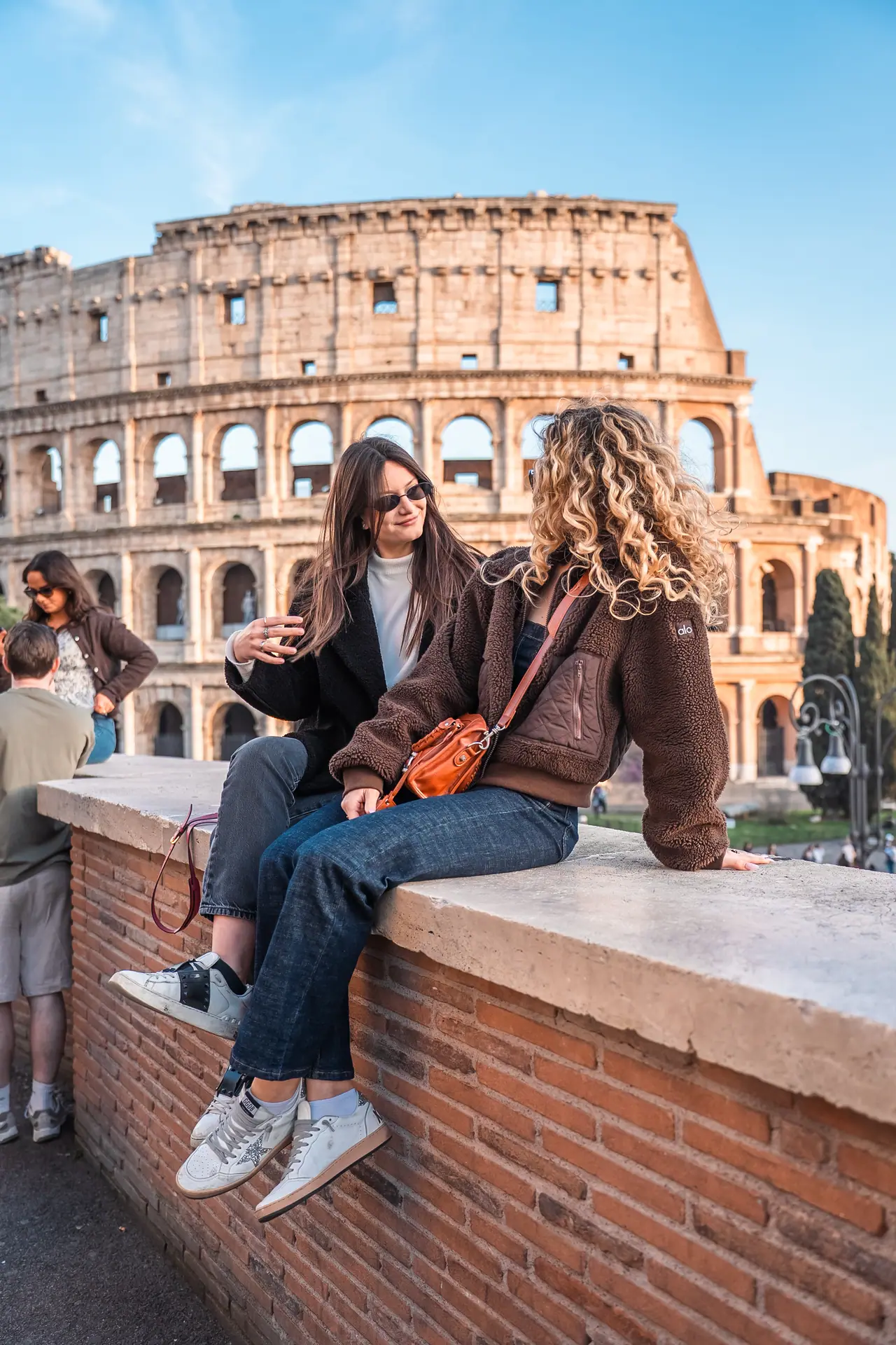 Due ragazze sedute davanti al Colosseo