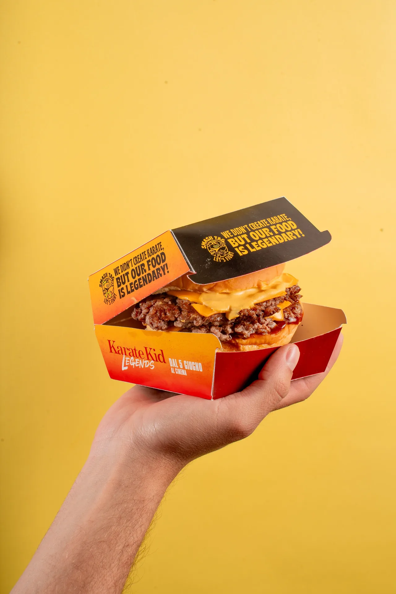Una mano tiene il box Smash Tag × Karate Kid con il burger