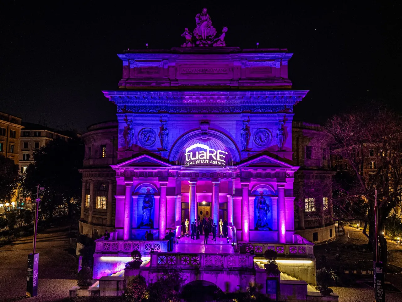 Il palazzo illuminato di viola con il logo Tuare